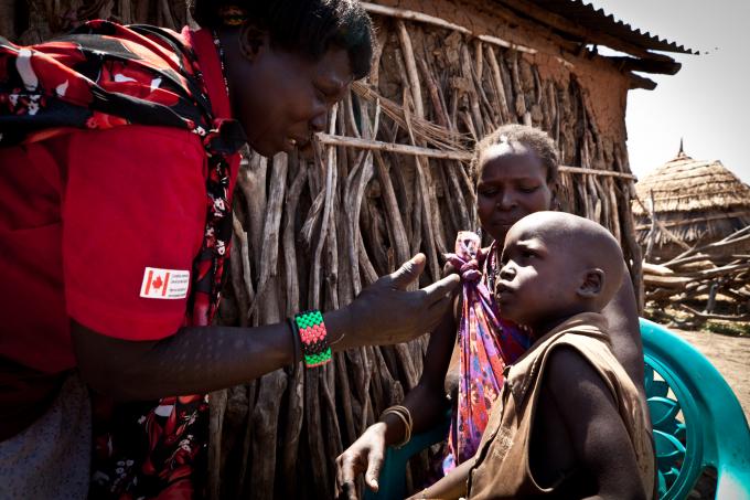 A Save the Children community health worker, Cecilia, performs a follow up check on 2-year-old Loge who had been suffering from pneumonia. (Colin Crowley/Save the Children)