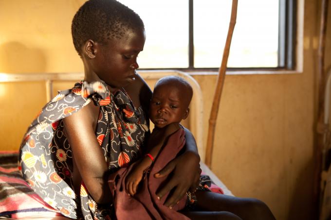 7-year-old Namana holds her 7 month old sister Tome who is being treated for malnutrition at a centre supported by Save the Children in Kapoeta North, Eastern Equatoria state, South Sudan (Colin Crowley/Save the Children)